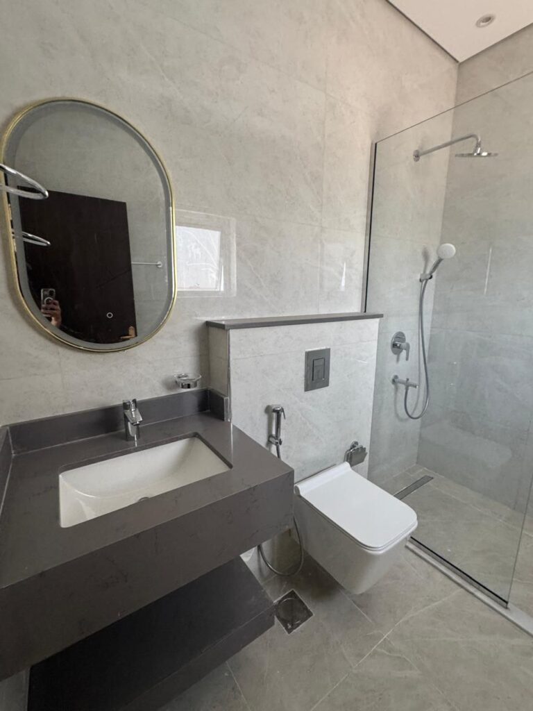 حمام فخم بتصميم رخامي أبيض بالكامل، يظهر النظافة والفخامة في التفاصيل الداخلية.